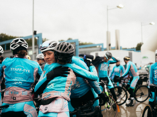 A group of people wearing helmets hug each other.