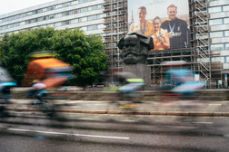 Eine Gruppe von Menschen fährt mit dem Fahrrad auf der Brückenstraße, vor dem Karl Marx Monuement entlang.